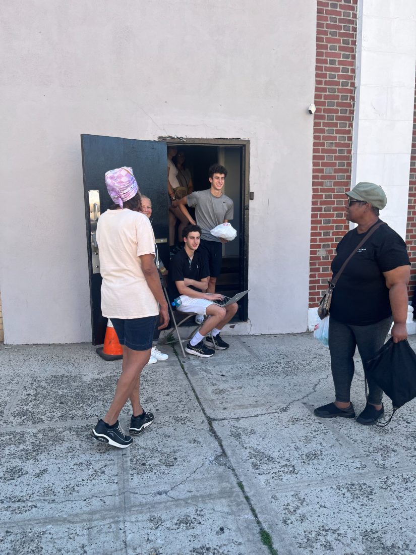 Daniel handing a bag of food to a neighbor at the kitchen door
