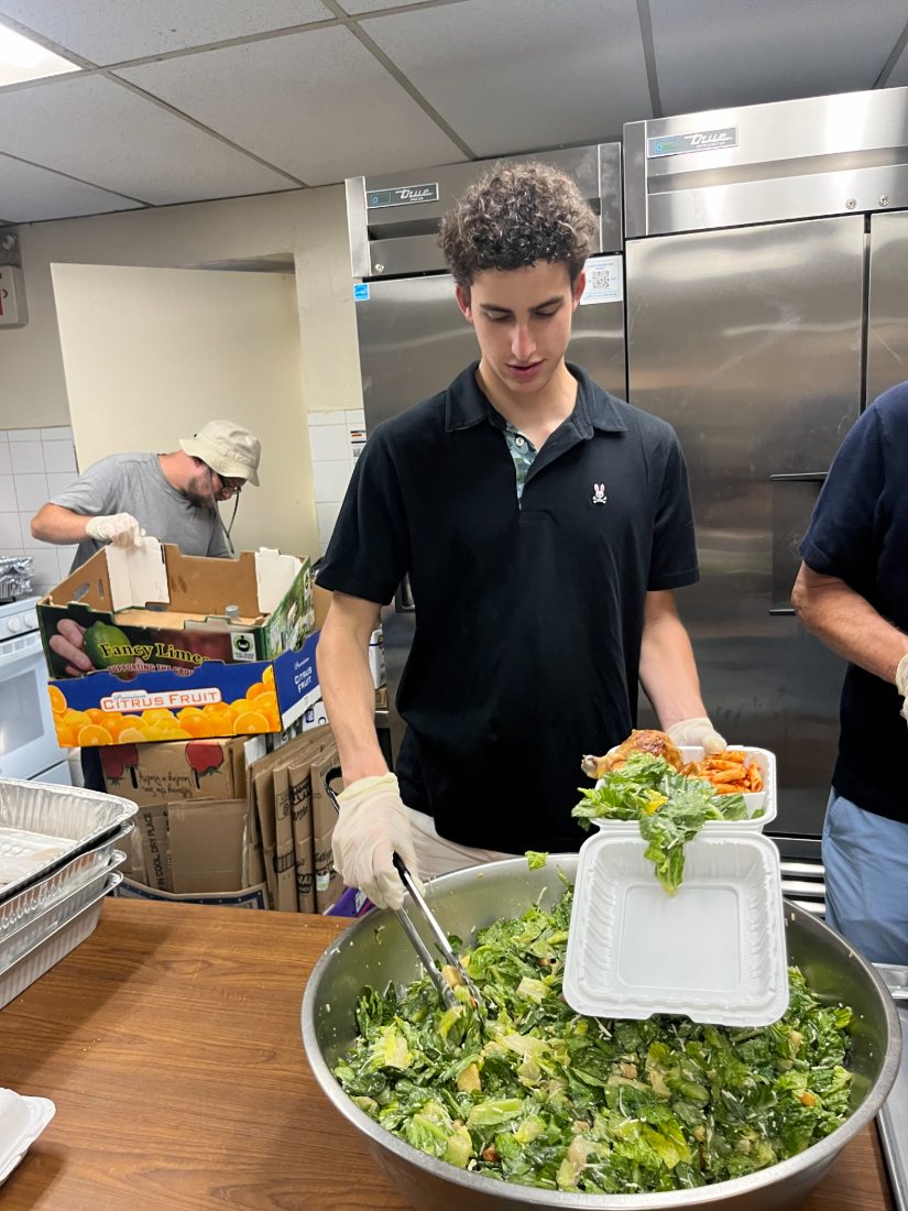 Liam packing a salad and chicken meal beside crates of citrus