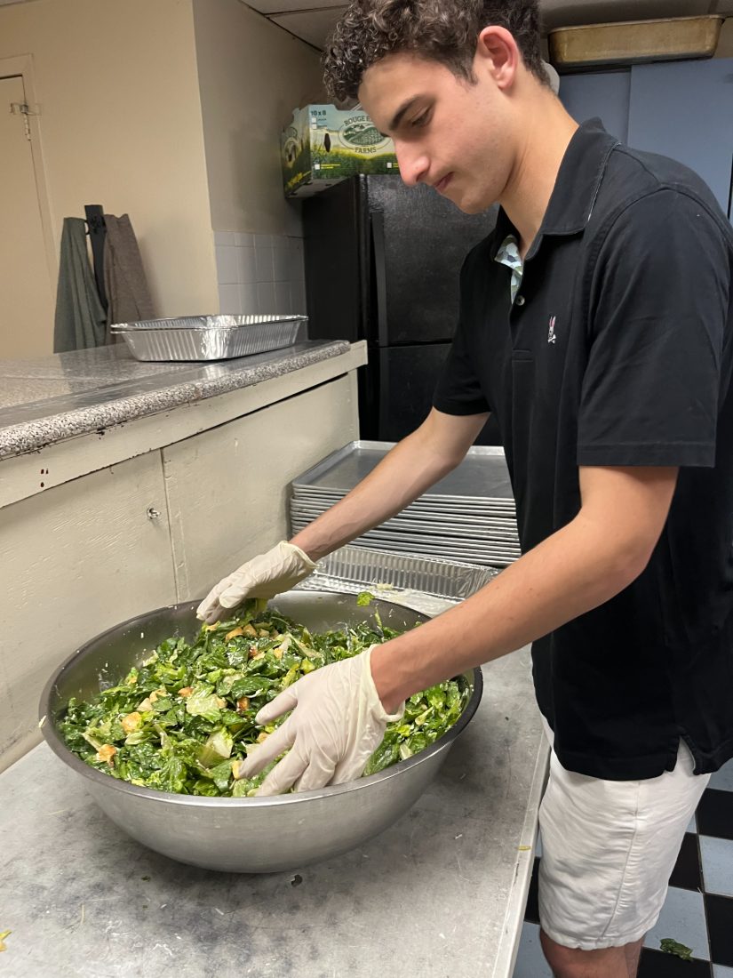 Liam tossing a large bowl of caesar salad