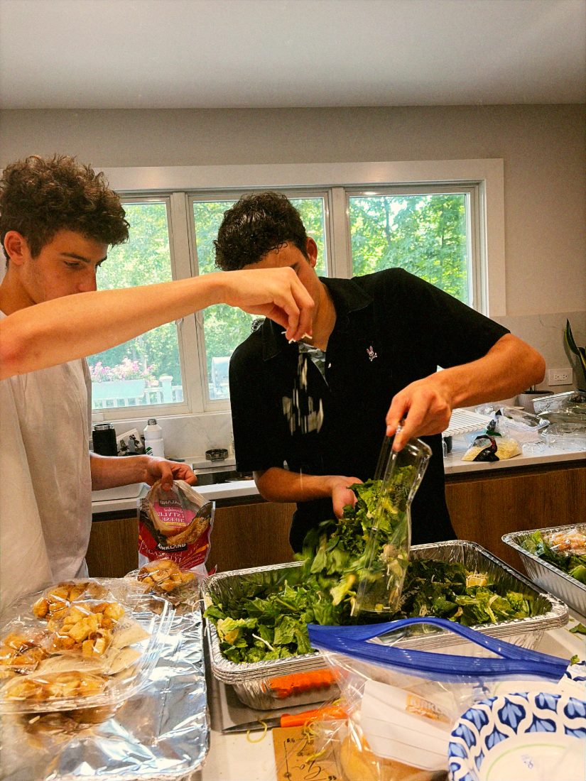 Daniel and Liam topping salad trays with cheese